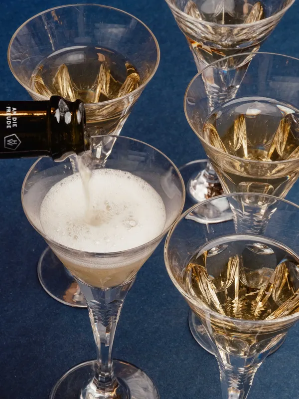 Sparkling wine being poured into coupes and tulip glasses