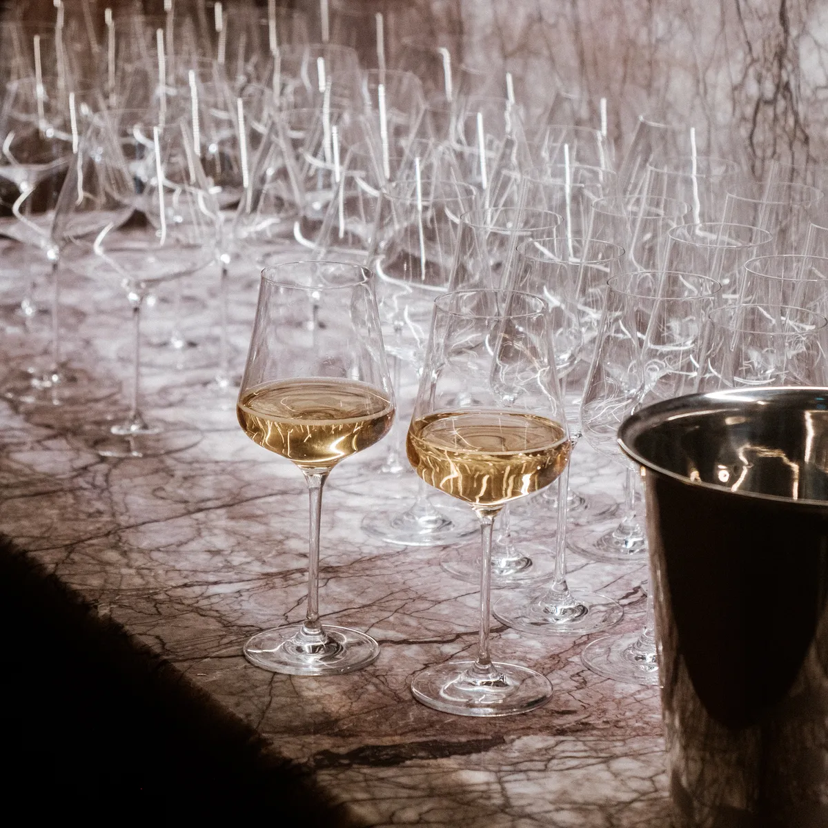 Two filled glasses in front of many empty glasses and an ice bucket