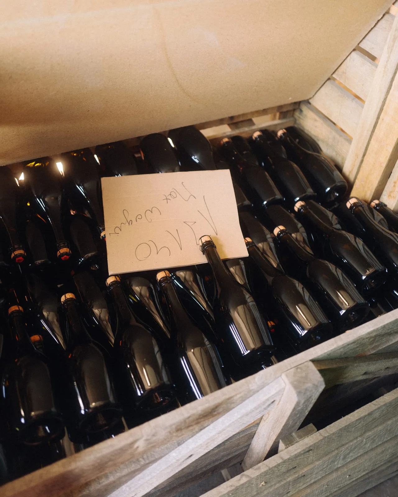 Wooden crate full of sparkling wine bottles with a handwritten note